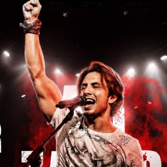 Ali Zafar mid-performance, one fist raised, singing into the mic under stage lights